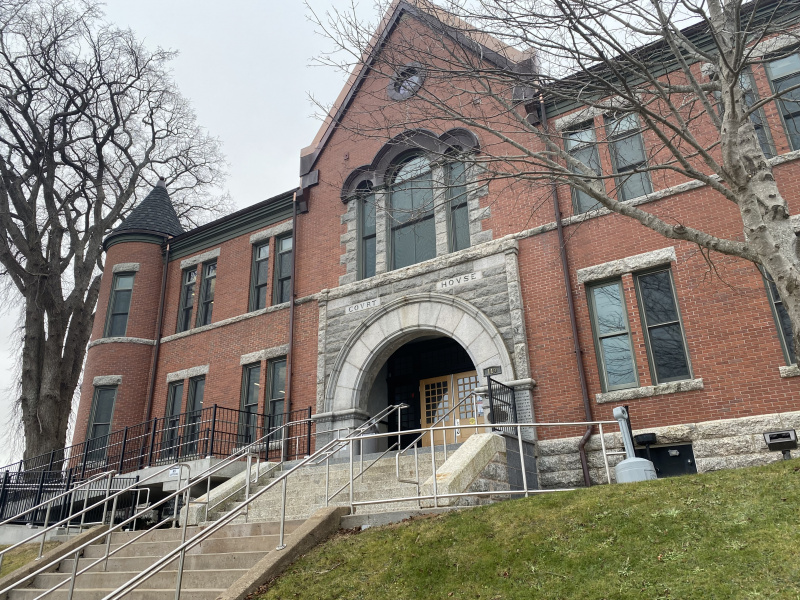 Large red brick courthouse with a stone staircase leading to the front entrance. 