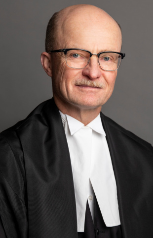 White man with glasses wearing black and white judicial robes.
