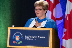 Female judge standing in front of a podium with a Canadian flag behind her.