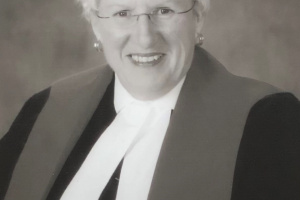 Black and white photo of a female judge wearing glasses. 