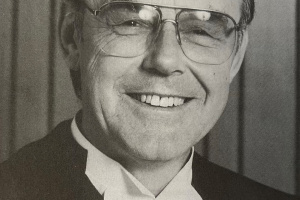 Black and white photo of a man in glasses and judicial robes. 